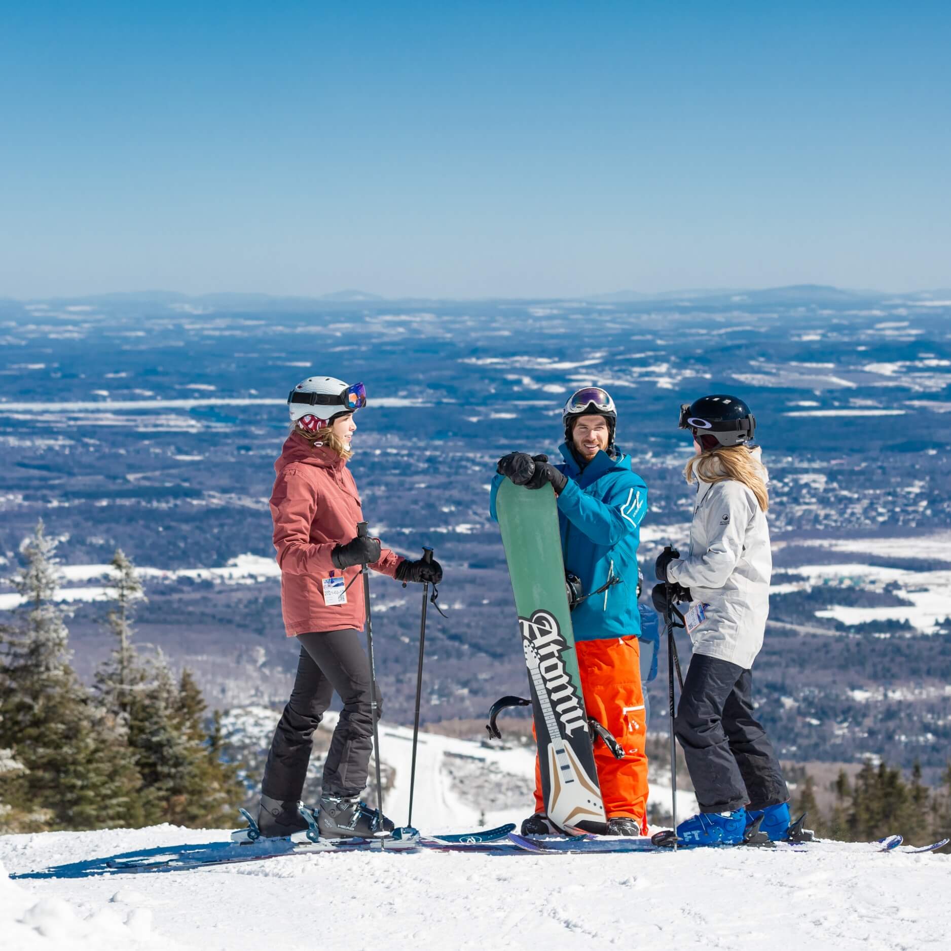 3 personnes qui font du ski et de la planche au sommet du Mont Orford